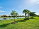 Scenic backyard with a tranquil lake view, palm trees, lush green lawn, and clear blue sky at 13862 Miranese St, Venice, FL 34293