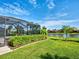 Lush backyard featuring a screened lanai, private pool, well-manicured lawn, and tranquil lake view at 13862 Miranese St, Venice, FL 34293