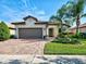 Inviting home with a well-maintained lawn, colorful landscaping, and a brick-paved driveway leading to a two-car garage at 13862 Miranese St, Venice, FL 34293