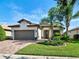 Charming single-story home with a well-manicured lawn, lush landscaping, and a brick driveway at 13862 Miranese St, Venice, FL 34293