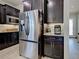 A kitchen featuring stainless steel refrigerator, dark cabinets, tile backsplash, and tiled floor at 13862 Miranese St, Venice, FL 34293