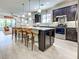 Spacious kitchen featuring an island with seating, stainless steel appliances, and dark cabinetry at 13862 Miranese St, Venice, FL 34293