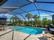Inviting screened-in pool with patio furniture, grill, and views of surrounding palm trees and lake at 13862 Miranese St, Venice, FL 34293