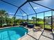 Relaxing screened-in pool area with a barbecue grill, lounge chairs, and scenic views of the surrounding greenery at 13862 Miranese St, Venice, FL 34293