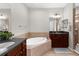 A bathroom with a soaking tub, dark wood cabinets, double mirrors, and tile floors at 2396 Caraway Dr, Venice, FL 34292