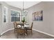 Bright dining area with a modern chandelier, white table, wood chairs, and a large window at 2396 Caraway Dr, Venice, FL 34292