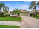 Charming single-story home featuring a well-manicured lawn, mature palm trees, and a paver driveway at 2396 Caraway Dr, Venice, FL 34292