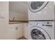 Compact laundry area featuring a stacked washer and dryer unit and utility sink at 334 7Th N Ave, Tierra Verde, FL 33715