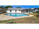 An in-ground backyard pool surrounded by a patio, an enclosed porch and lush greenery, creating a private retreat at 7405 Clearview Dr, Tampa, FL 33634