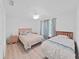 Cozy bedroom featuring two beds, wood-look floors, and a window for natural light at 7438 Gulf Way, Hudson, FL 34667