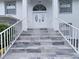 Elegant front entrance with tiled steps, white railings, and a stylish double door at 7438 Gulf Way, Hudson, FL 34667