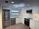The newly remodeled kitchen has stainless steel appliances, white cabinets and a geometric light fixture at 12550 Capri N Cir, Treasure Island, FL 33706