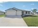 Two-car garage, gray siding, and landscaping at 14074 Ginnie Springs Way, Parrish, FL 34219