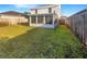 An open grass backyard featuring a screened in patio with a wood fence at 30208 Rattana Ct, Wesley Chapel, FL 33545