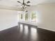 Bright bedroom featuring dark wood floors, ceiling fan, and multiple windows allowing natural lighting at 30208 Rattana Ct, Wesley Chapel, FL 33545