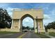Ornate entrance archway to a community with a globe centerpiece and lush landscaping at 2386 Sumatran Way # 26, Clearwater, FL 33763