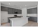 Modern kitchen featuring gray cabinets, stainless steel appliances, and a large white island at 9593 Vibrant Lane, Venice, FL 34292