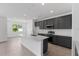 Well-lit kitchen with gray cabinets, a white island, and stainless steel appliances at 9593 Vibrant Lane, Venice, FL 34292