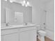 Bathroom with dual vanity, white cabinets, quartz countertop, large mirror, shower and tile flooring at 9577 Vibrant Lane, Venice, FL 34292
