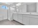 Bathroom with dual vanity, white cabinets, quartz countertop, shower with glass doors and tile flooring at 9577 Vibrant Lane, Venice, FL 34292