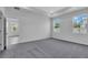 Bedroom with neutral paint, two large windows, carpet flooring and open bathroom at 9577 Vibrant Lane, Venice, FL 34292