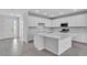 Modern kitchen with white cabinets, a large island with quartz countertops, and stainless steel appliances at 9577 Vibrant Lane, Venice, FL 34292