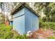 Blue storage shed in a wooded backyard setting at 34392 Broken Stone St, Webster, FL 33597