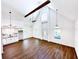 Open living room with vaulted ceilings, exposed beam, and wood floors at 34392 Broken Stone St, Webster, FL 33597