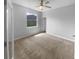 Bright bedroom features a ceiling fan, plush carpet, and a window that fills the room with natural light at 33083 Windelstraw Dr, Wesley Chapel, FL 33545