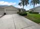 Charming single-story home featuring a two-car garage, palm trees and a lush front lawn at 33083 Windelstraw Dr, Wesley Chapel, FL 33545