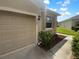 Beige garage door with house number, neat landscaping, and a manicured lawn at 33083 Windelstraw Dr, Wesley Chapel, FL 33545