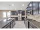 Modern kitchen with granite countertops, stainless steel appliances, and dark cabinets at 8235 Bird Whistle Ln, Land O Lakes, FL 34637