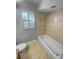 Tiled bathroom features a bathtub with tiled surround and a window for natural light at 3184 Wessex Way, Clearwater, FL 33761