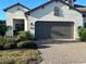 Inviting single-story home with a brown double garage door, white exterior, and lush landscaping at 11145 Mcdermott Ct, Englewood, FL 34223