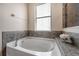 Bathroom with a garden tub, gray tile, and window at 6722 Wild Elm Ct, Wesley Chapel, FL 33545
