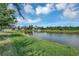 Pond-side backyard with lush green grass and neighborhood view at 6722 Wild Elm Ct, Wesley Chapel, FL 33545