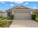 Tan one-story house with a two-car garage and grey front door at 12120 Barnsley Reserve Pl, Gibsonton, FL 33534
