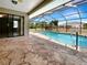 Covered patio with view of pool surrounded by a screened enclosure and stone pavers at 9308 San Bernandino Ave, Englewood, FL 34224