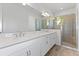 Bright bathroom with double sinks, white cabinets, quartz countertop, and glass-enclosed shower with tile surround at 9584 Vibrant Lane, Venice, FL 34292