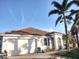 White house with brown tile roof, two-car garage, and palm trees at 17274 Asmara Ct, Punta Gorda, FL 33955