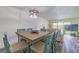 Dining area with light wood table, teal chairs, and view of living room at 29200 Bay Hollow Dr # 3290/3292, Wesley Chapel, FL 33543