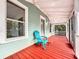 Relaxing front porch with red painted flooring and teal house at 210 15Th E St, Bradenton, FL 34208