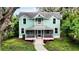 Two-story light teal home with a wrap around porch at 210 15Th E St, Bradenton, FL 34208