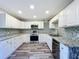 Modern kitchen with white cabinets, granite counters, and stainless steel appliances at 210 15Th E St, Bradenton, FL 34208
