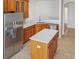 Open kitchen featuring stainless steel refrigerator, island and custom wood cabinetry at 2302 123Rd E Pl, Parrish, FL 34219