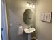Stylish half bathroom with pedestal sink, oval mirror and decorative art at 7224 Ketch Pl, Bradenton, FL 34212