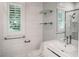 Modern bathroom featuring tiled walls, white cabinets, glass shelves and a shower with glass doors at 236 20Th Ave Se, St Petersburg, FL 33705