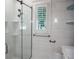 Bathroom featuring glass shower enclosure, tiled walls, and plantation shutters for natural light at 236 20Th Ave Se, St Petersburg, FL 33705