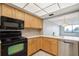 Kitchen with black appliances and light wood cabinets with view to dining area at 6219 Palma Del Mar S Blvd # 301, St Petersburg, FL 33715