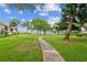 Concrete pathway meanders through grassy area with lush landscaping and water views at 6219 Palma Del Mar S Blvd # 301, St Petersburg, FL 33715